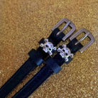 Black leather skull and crossbones ManeJane spur straps on a gold glitter background