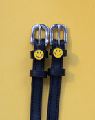 Pair of smiley-face spur straps laid flat on a yellow background