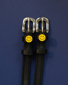 Black leather smiley-face ManeJane spur straps flat on a navy background