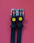Pair of yellow smiley spur straps laid flat on a pink-red background