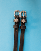 Black snowflake spur straps with rhinestone snowflake charms on a light blue background