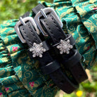 Snowflake spur straps with crystal charms draped over green floral fabric, ManeJane