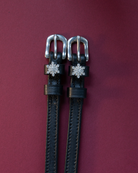Black leather snowflake spur straps with sparkling snowflake charms on a burgundy background
