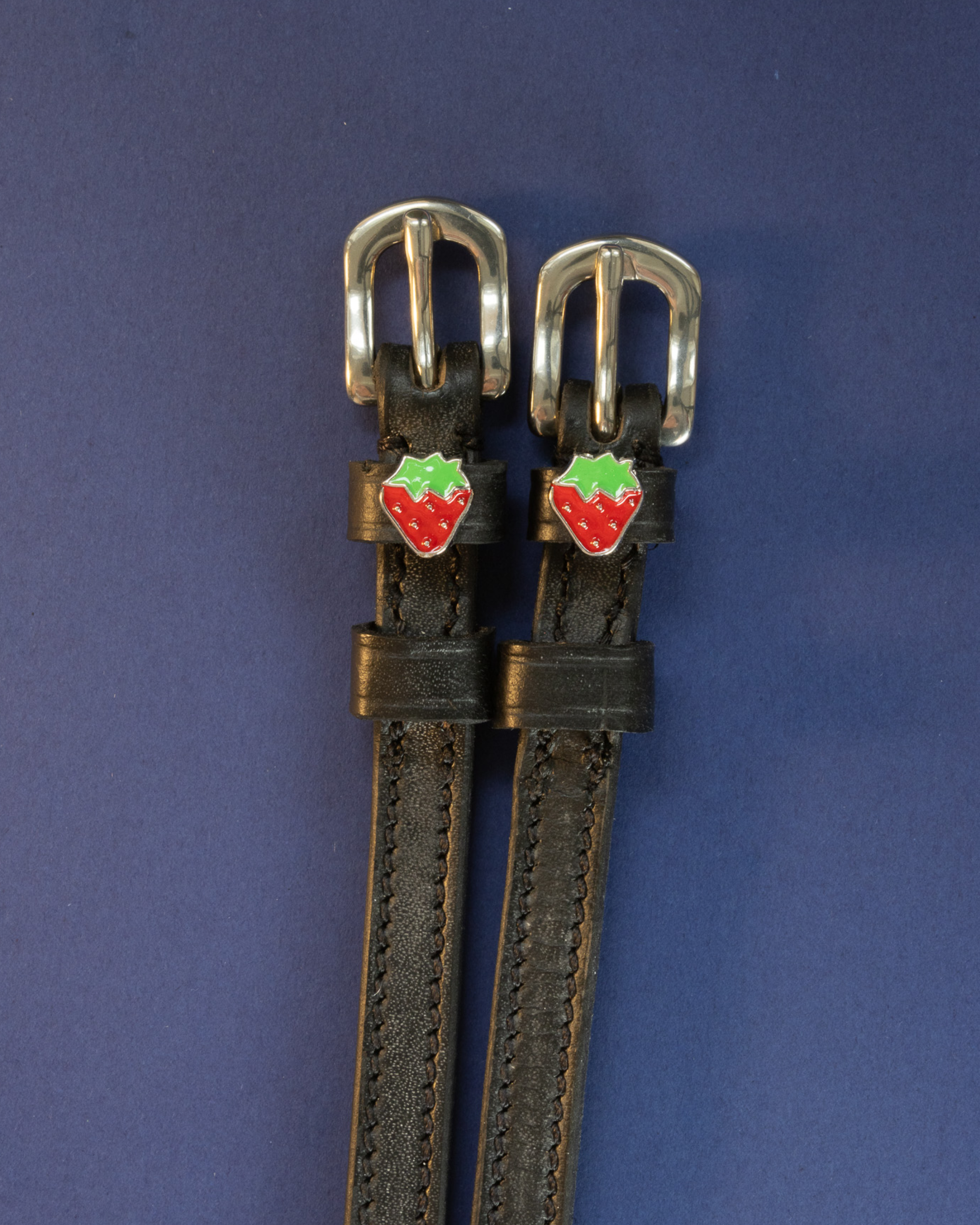 ManeJane strawberry spur straps with red-and-green strawberry charms on a navy background