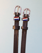 Brown leather ManeJane spur straps with red-white-blue tricolor flag charms and silver buckles