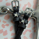 Close-up of silver 'The Boss' star charms on black leather spur straps beside a metal bit