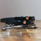 Black tiger spur straps coiled on a silver stirrup on a wooden table