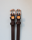 Brown leather tiger spur straps with rose-gold buckles and tiger-face charms