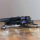 Black leather tri-color ribbon spur straps coiled on wood with a silver bit
