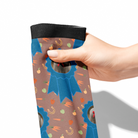 Hand holding custom blue ribbon patterned Dreamers & Schemers boot sock with stable snackies design