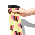 Hand holding custom heart socks featuring repeated dog images on yellow background with pink hearts