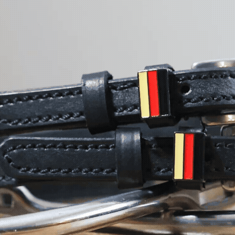 Black leather German Flag Spur Straps with stainless steel buckle and custom charm displayed on peg wall card