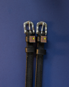 Pair of waffle-charm ManeJane spur straps flat on a navy background
