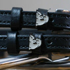 Black leather ManeJane spur straps with silver buckles and grey walrus charms on royal blue