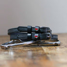 Black watermelon charm spur straps coiled beside a silver spur on a rustic wood surface