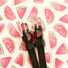 Dark leather ManeJane watermelon spur straps with silver buckles on a navy blue background