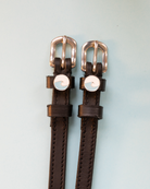 Dark brown leather ManeJane spur straps with blue wave charms and rose gold buckles
