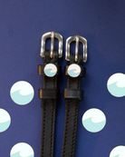 Black leather wave spur straps on a navy background with a wave polka-dot pattern