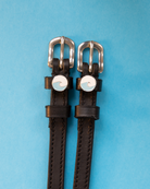 Black leather ocean wave spur straps on a light blue background