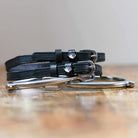 Black leather Wild Shark spur straps coiled beside a silver spur on a wood surface