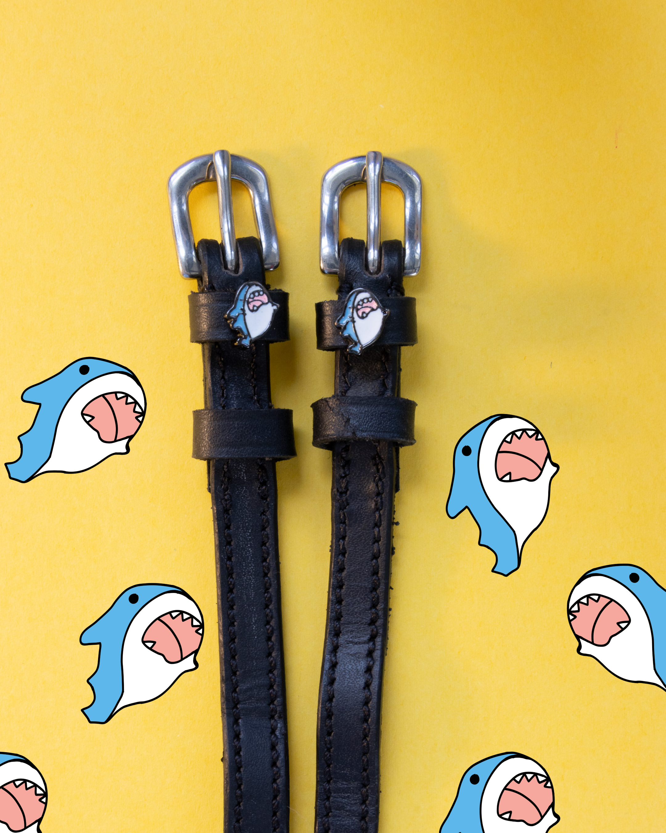 Black leather shark spur straps on yellow with scattered cartoon shark illustrations