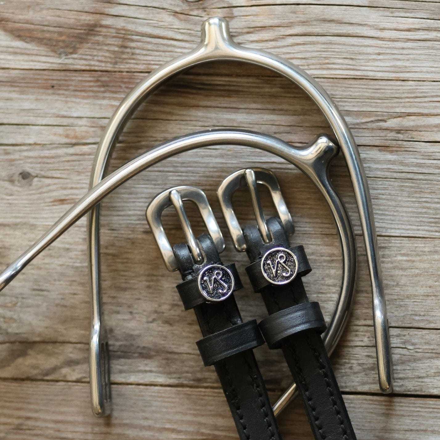Capricorn Spur Straps black leather with stainless steel buckles and custom charm on wooden background