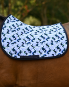 Dino-skate saddle pad in pale periwinkle with navy skating dinosaurs, shown on a bay horse without a saddle