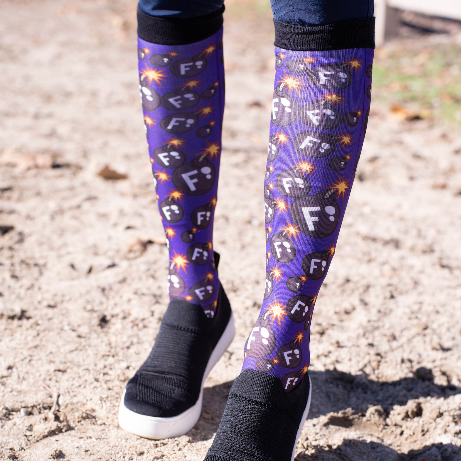 Ultimate F-Bomb Pack equestrian boot socks with bomb and F-letter design on rider's legs outdoors