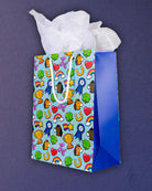 Full O' Luck medium gift bag angled right, blue gusset meeting the aqua panel of clovers and rainbows.