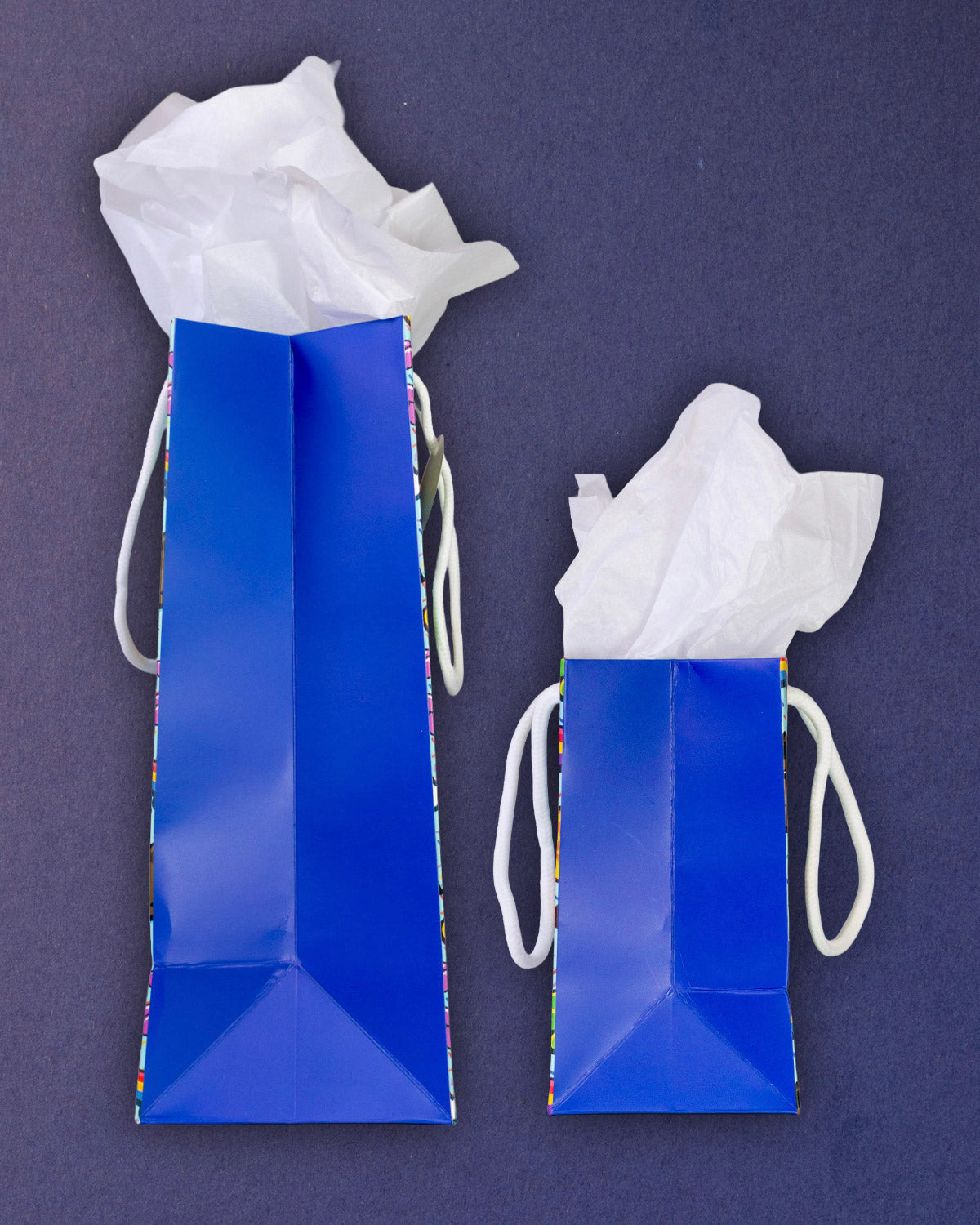 Full O' Luck gift bags in medium and small side by side, both royal blue side gussets facing out.