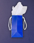 Full O' Luck small gift bag on its side, plain blue gusset and base fold with a strip of print at the edge.