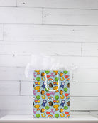 Full O' Luck medium gift bag on a white shelf, bright print of trophies, rosettes and four-leaf clovers.