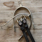 Gemini Spur Straps black leather with stainless steel buckles and custom charms on wooden background
