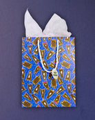 Hairy Styles medium gift bag front-on against navy, Tissue Included tag hanging from the rope handle.