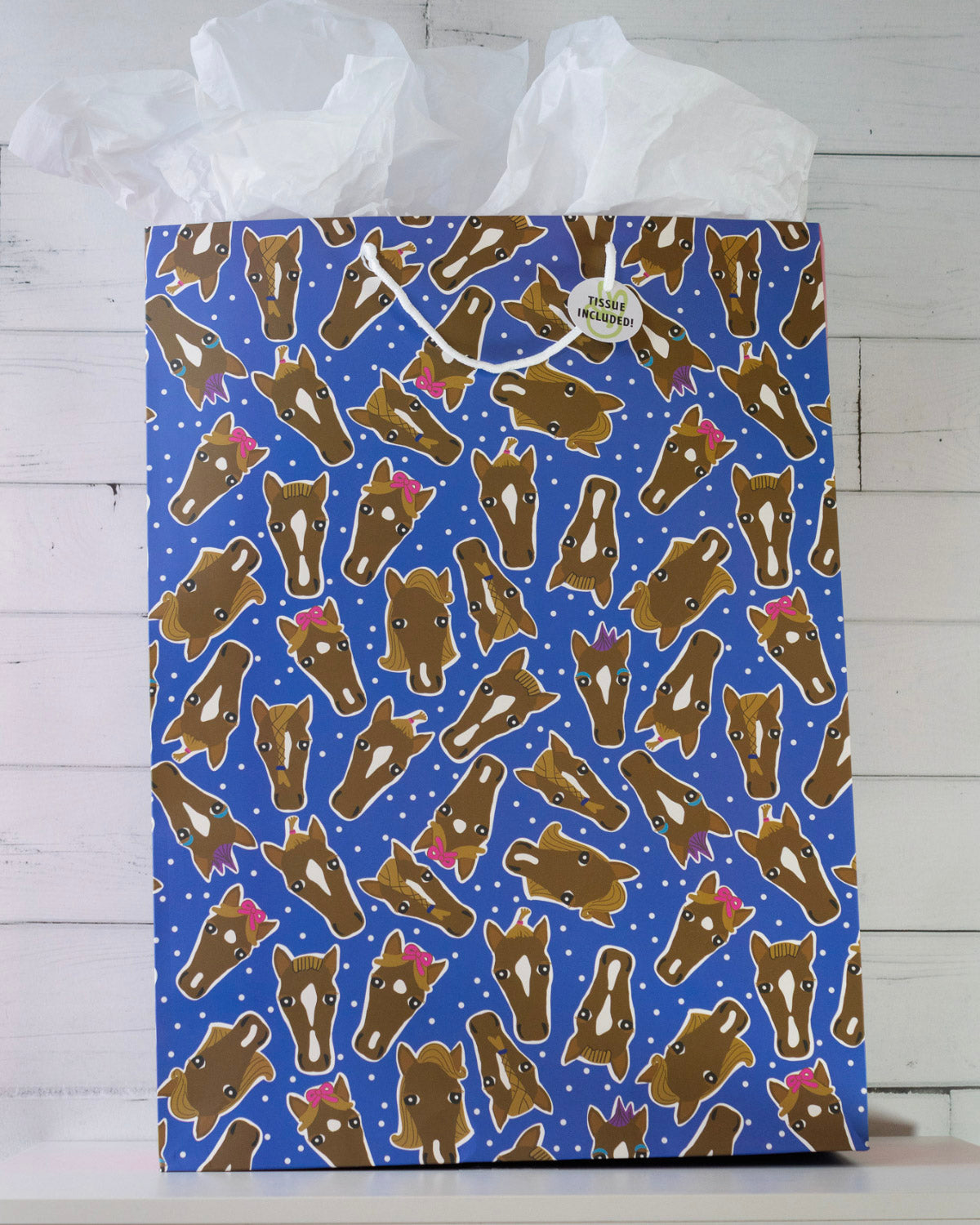 Hairy Styles large gift bag on a white shelf, royal blue panel of horse heads in braids, bows and ponytails.