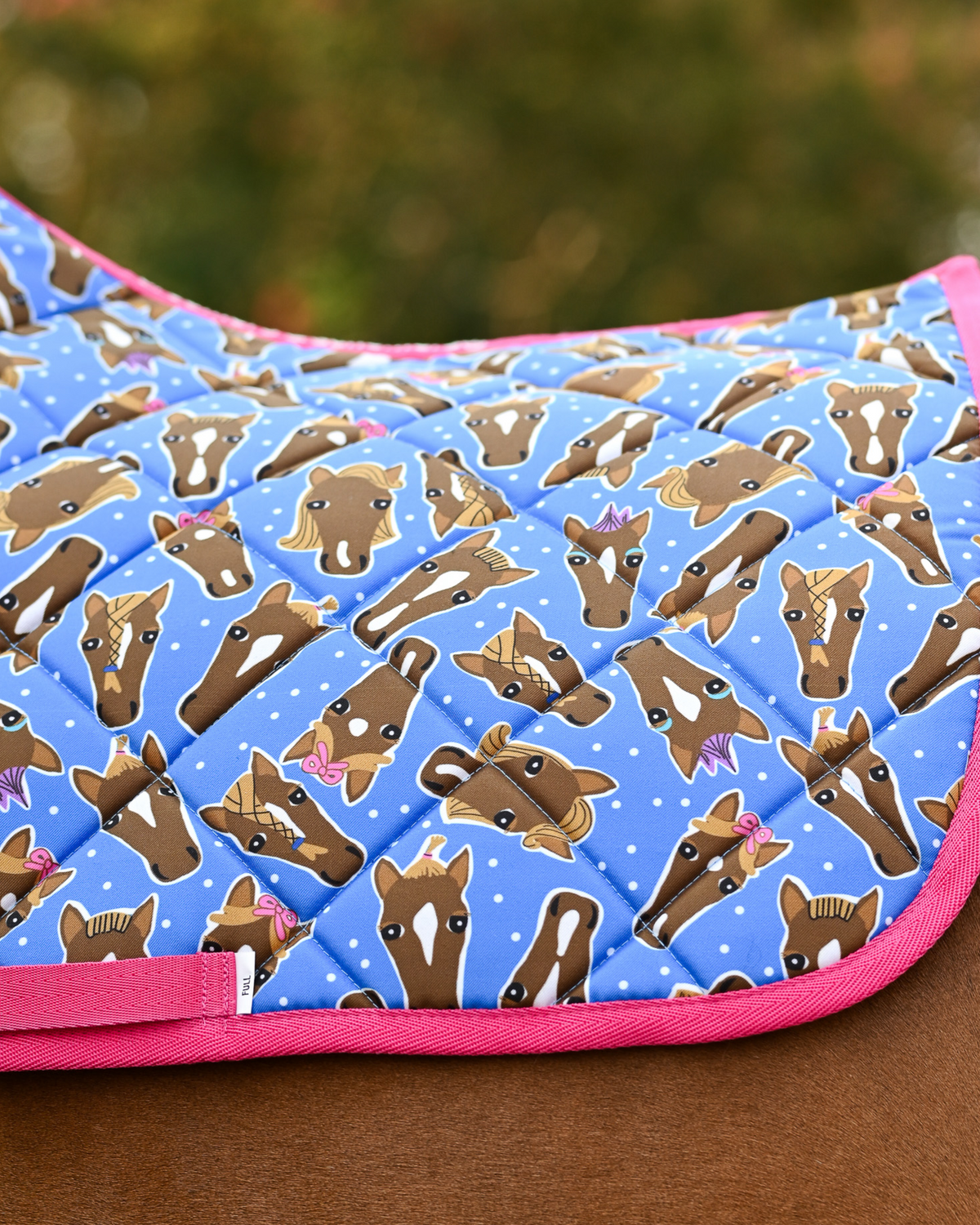 Close view of the Hairy Styles print — braided horse heads and white dots on blue, edged in hot pink