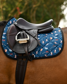 Side profile of the It's Not a Hobby saddle pad in dark teal beneath a brown jumping saddle