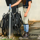 youth wearing blue patterned riding boot socks with horse designs and brown riding boots at barn