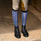 Blue "Keep Calm & Dreidel On" riding socks with Star of David and dreidel pattern worn with riding boots and beige breeches
