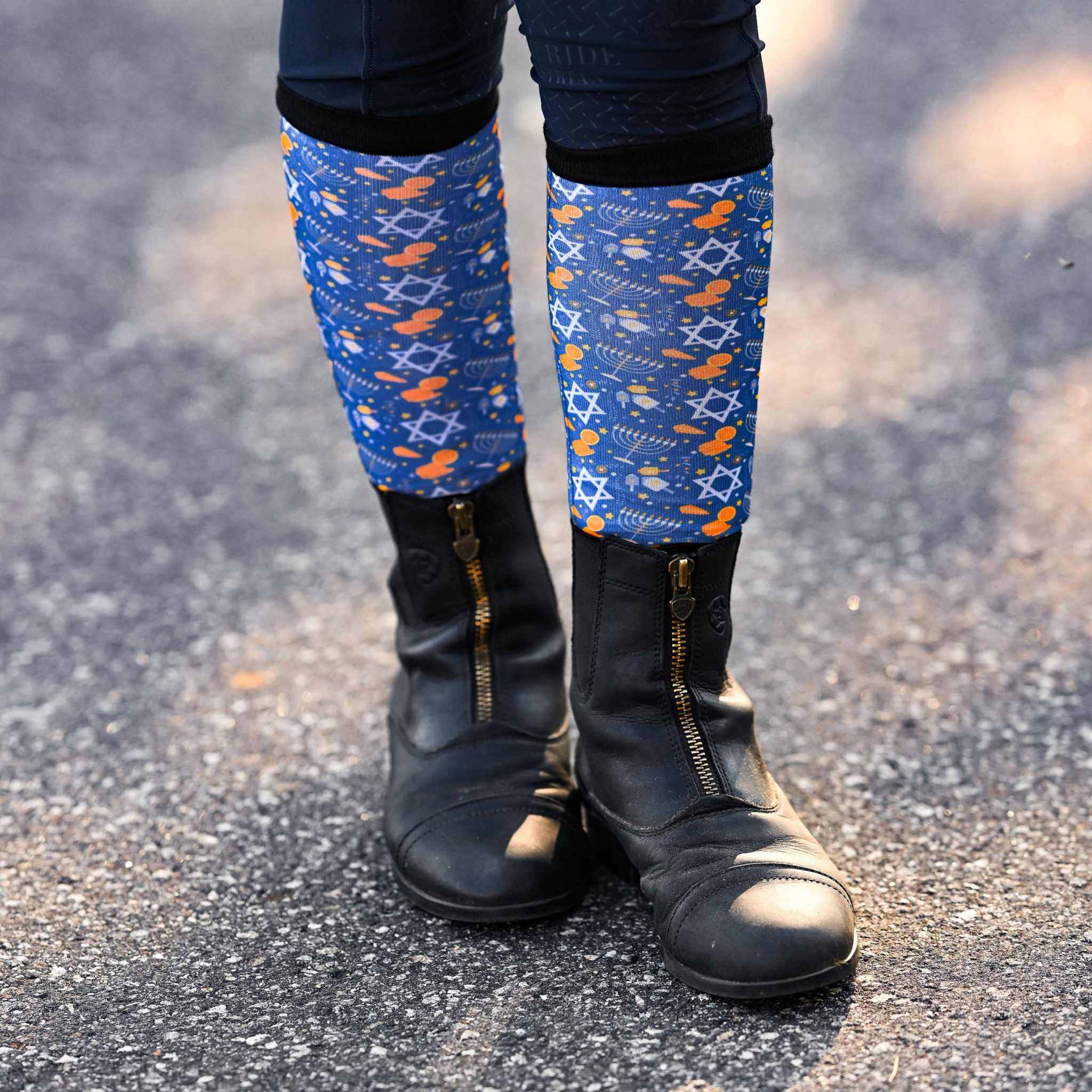 blue Keep Calm & Dreidel On riding socks worn with black riding boots on pavement