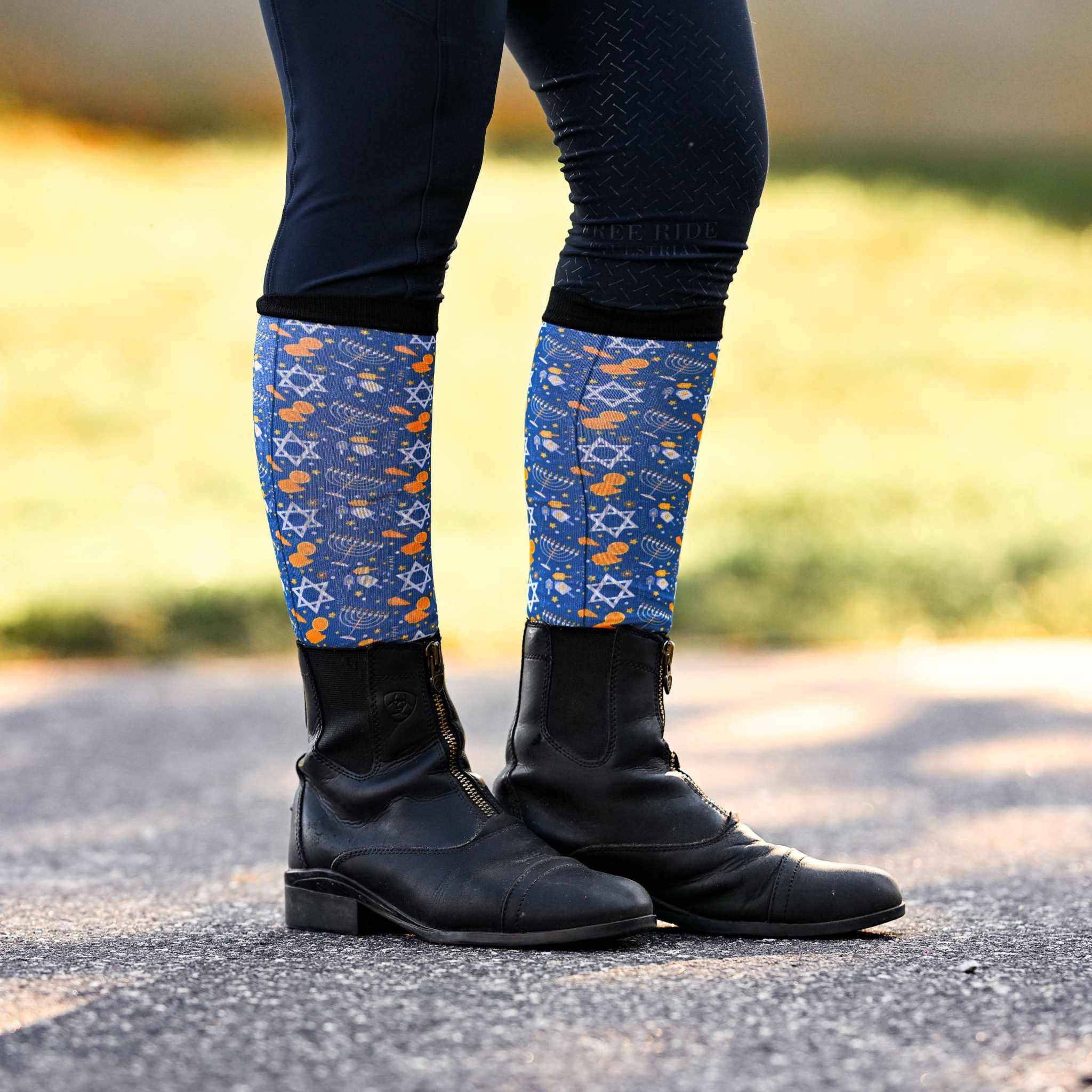 Keep Calm & Dreidel On holiday-themed riding socks with Star of David and dreidel patterns worn with black riding boots