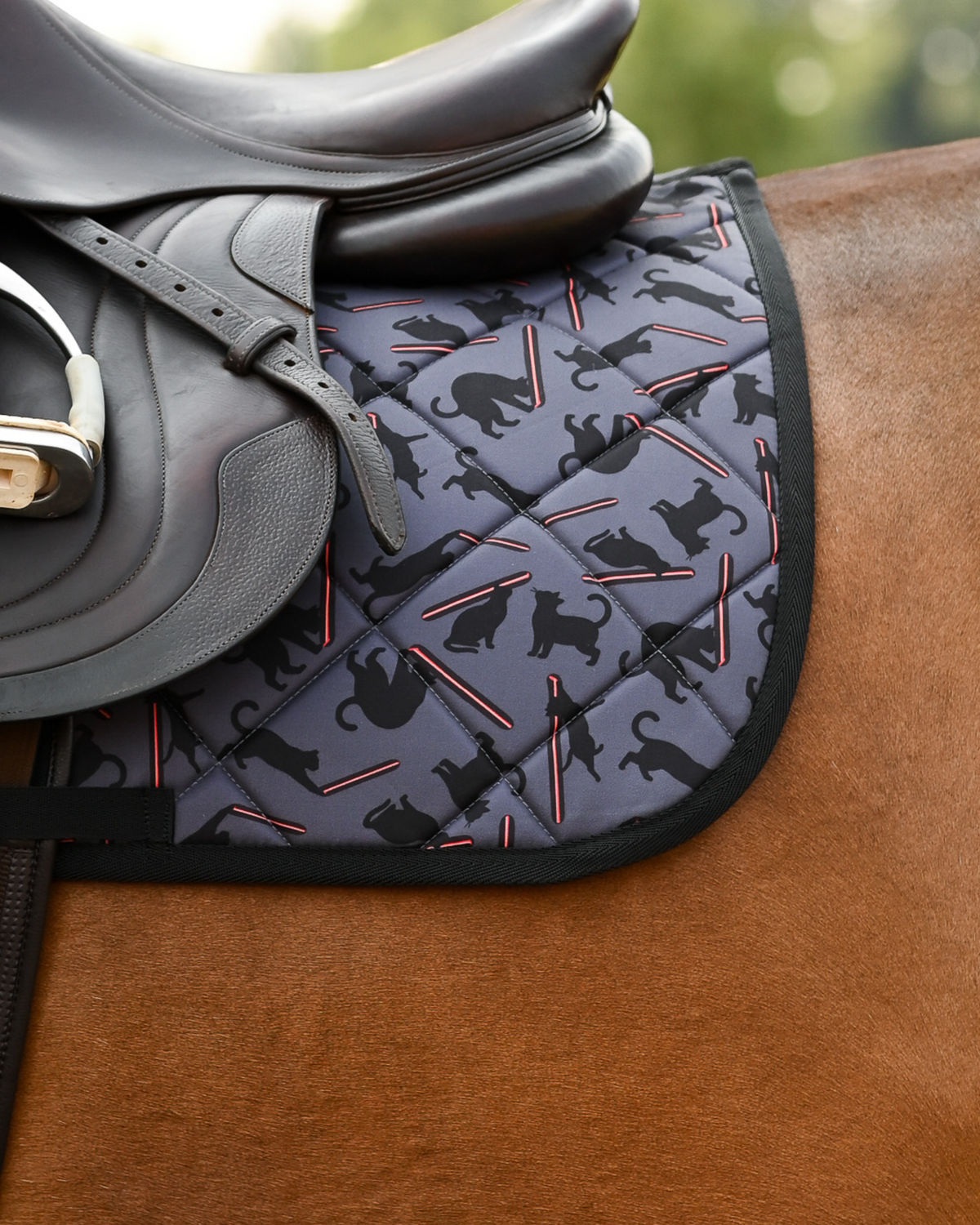 Laser Cats saddle pad in slate grey under a brown close-contact saddle, cats chasing red laser beams
