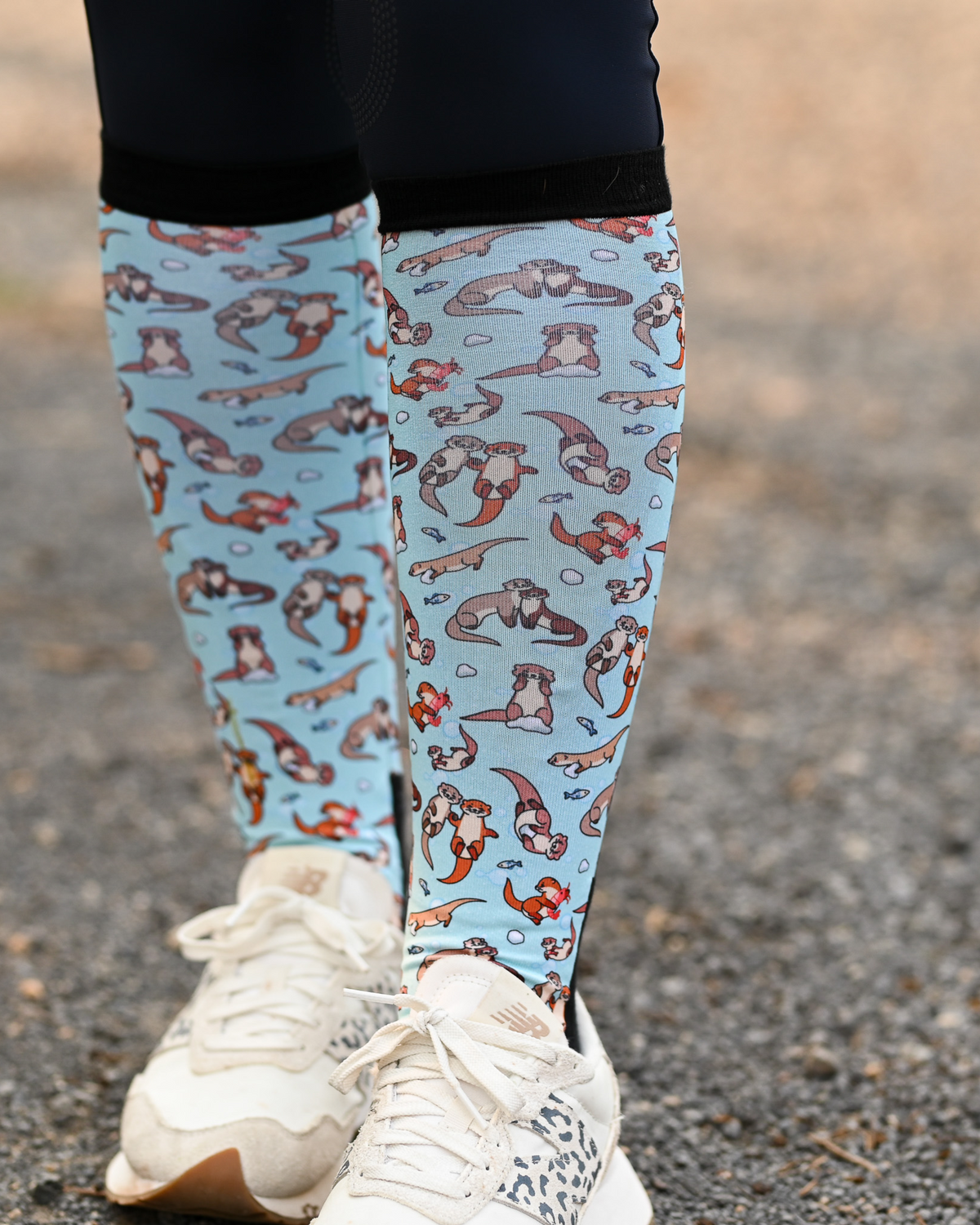 Otter-ly Adorable riding boot socks styled over breeches, pale blue with otters floating and holding hands
