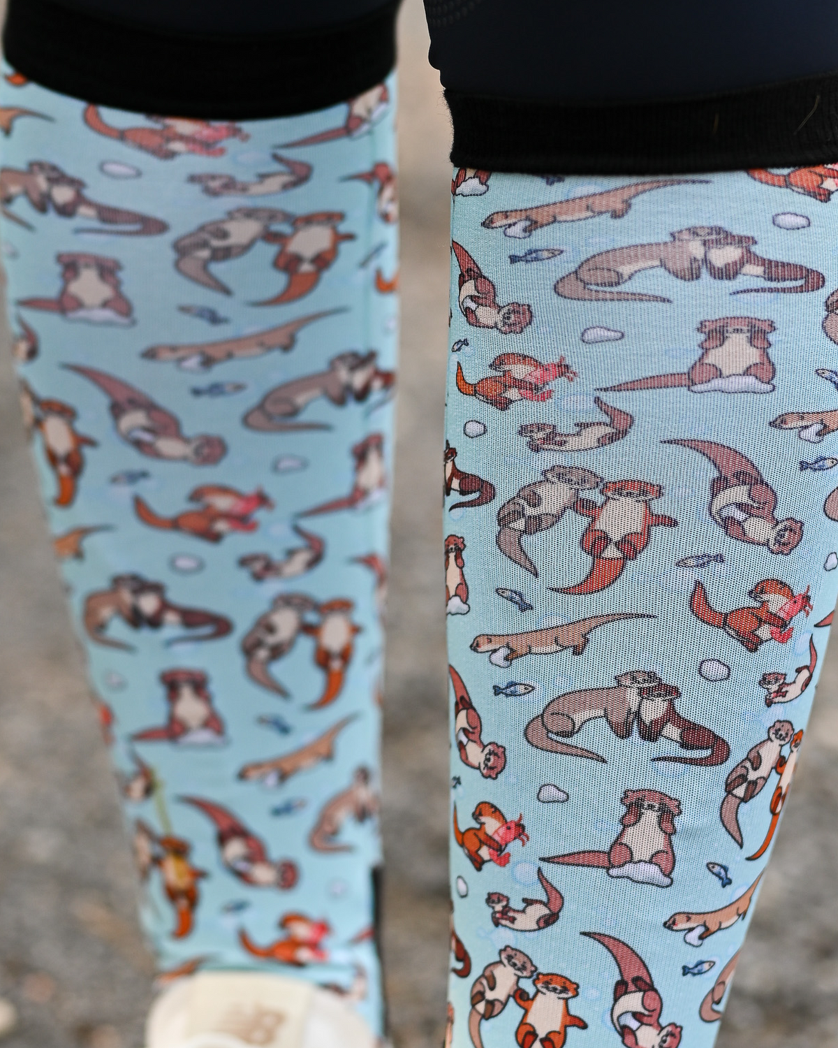 Close crop of the Otter-ly Adorable boot sock print, otters floating and holding hands on pale blue