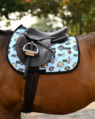 Pasture Ornaments holiday pad under a brown close-contact saddle, bauble horses on light blue quilting
