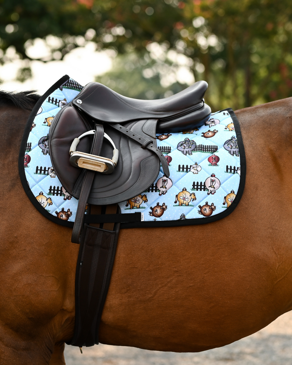 Pasture Ornaments holiday pad under a brown close-contact saddle, bauble horses on light blue quilting