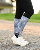 Pony Pilates riding boot socks styled over breeches, soft blue with horses stretching through yoga poses