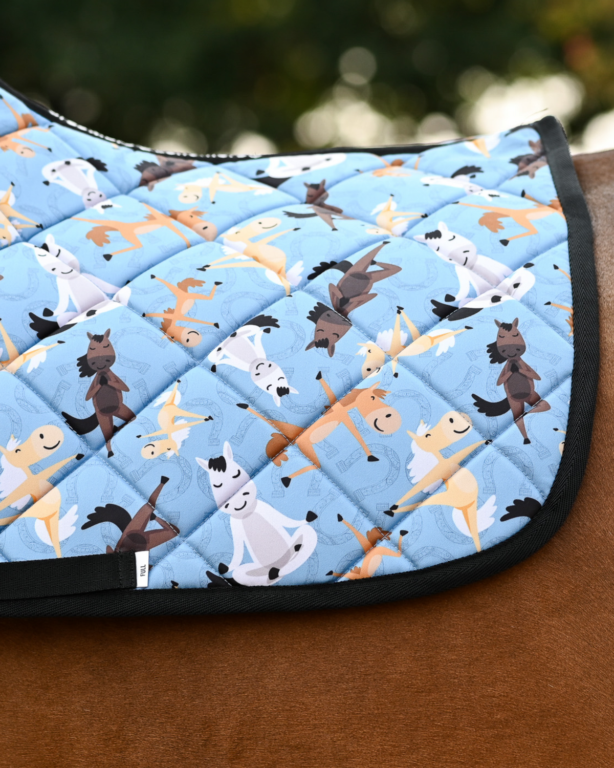 Close crop of the Pony Pilates print: horses in yoga poses over tonal horseshoes on denim blue