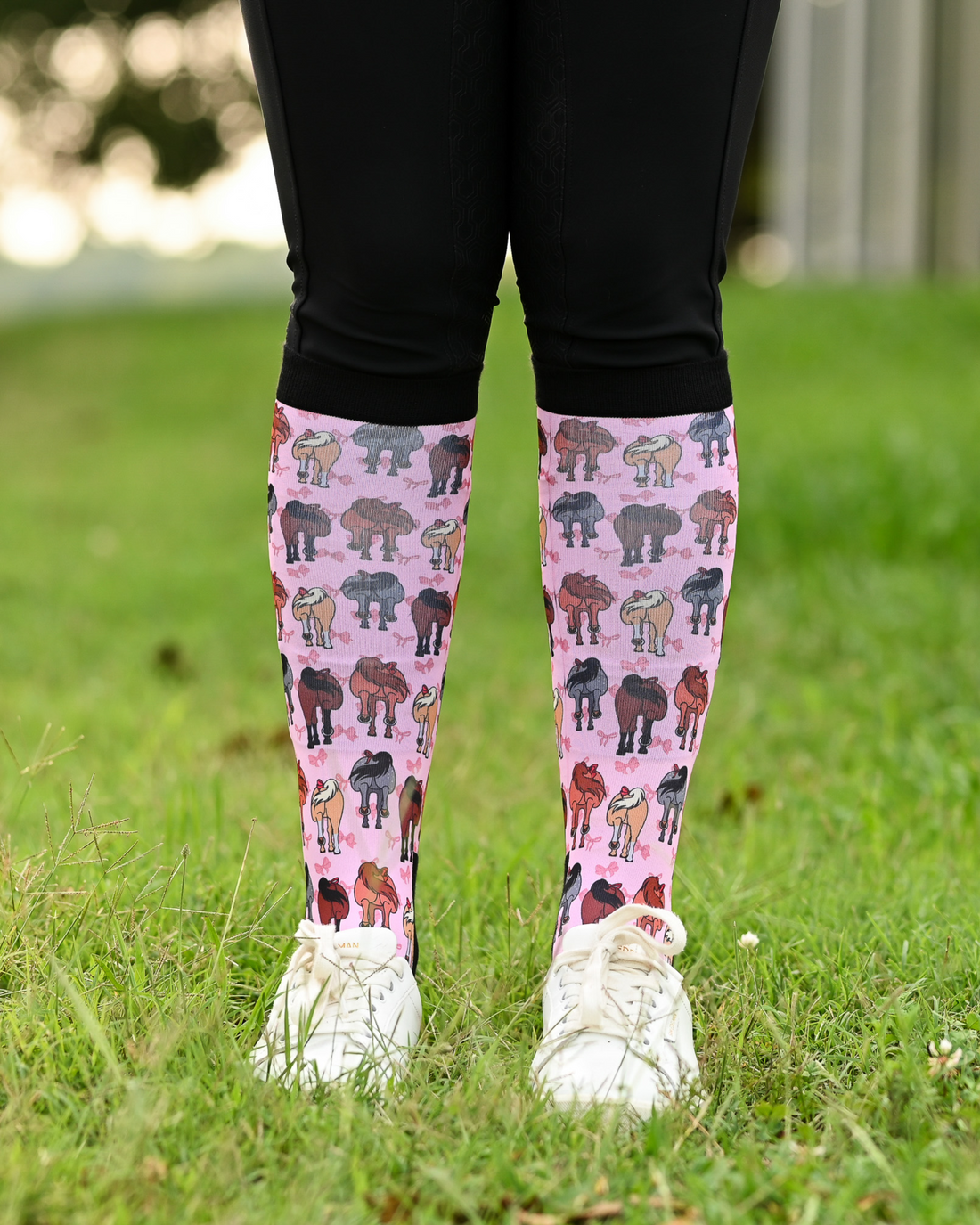 Red Ribbon Girlies boot socks seen from the front, pink ground scattered with horse hindquarters tied with red bows