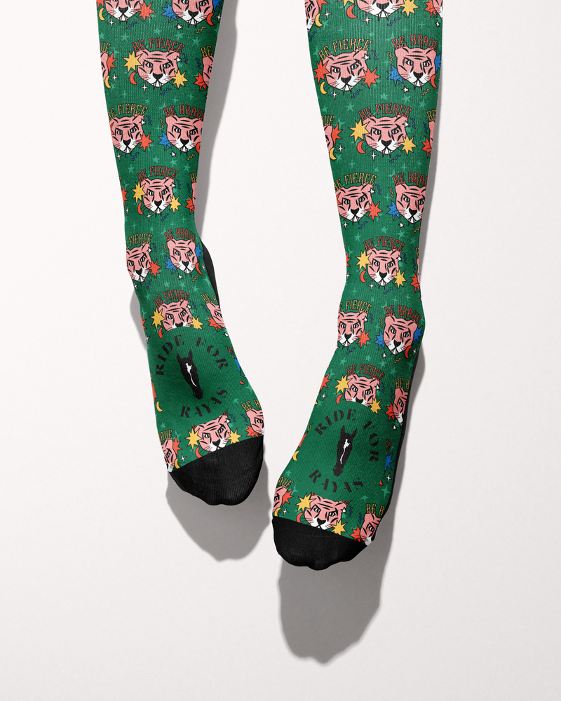 Be Brave socks seen from the toes, black toe caps and the Ride for Rayas horse logo on the green tiger print